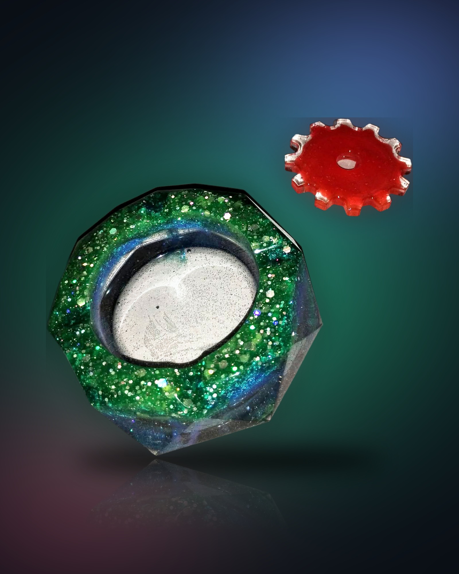 Faceted green and blue glitter resin dish beside a small red resin gear