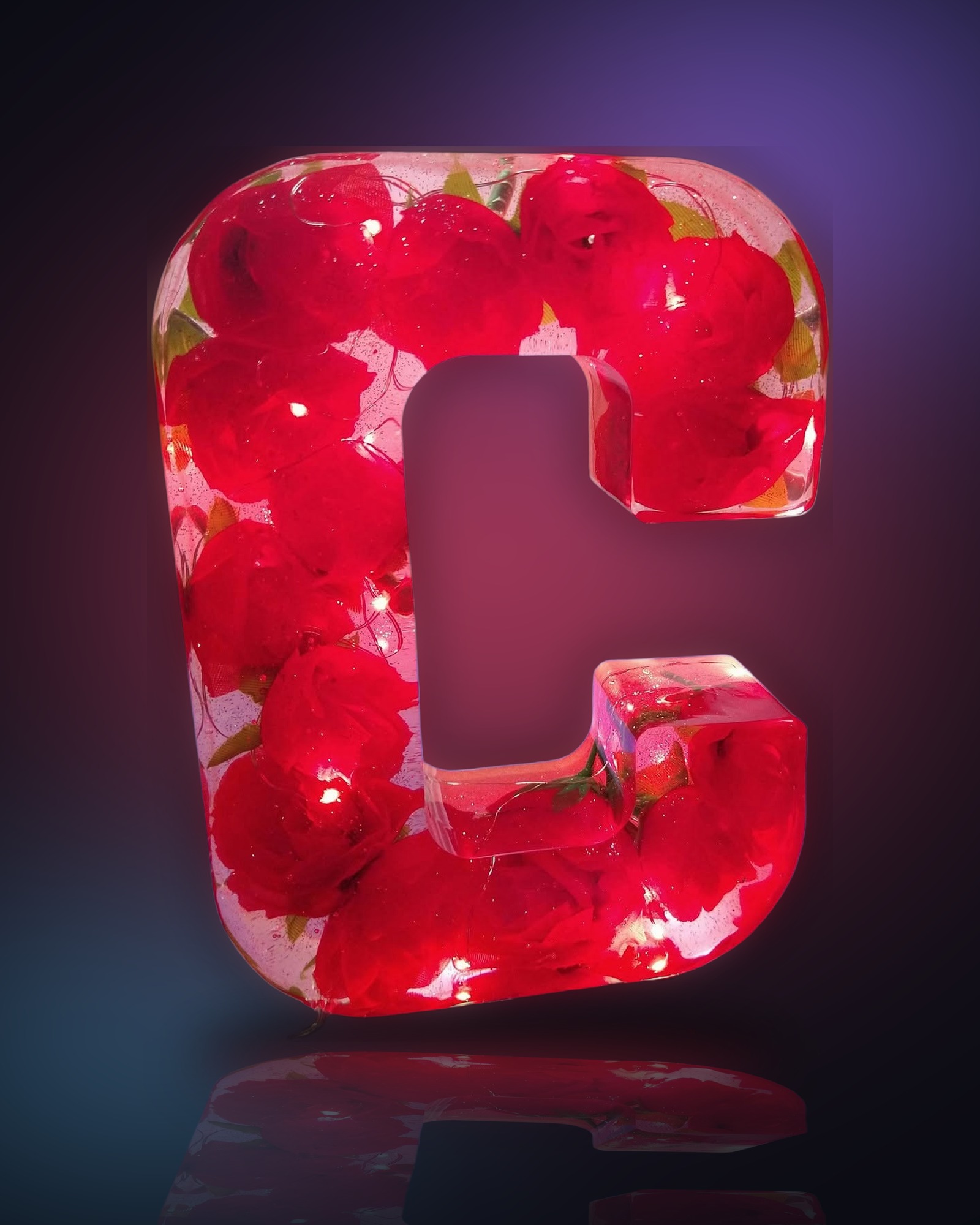 Handcrafted clear resin letter C filled with red roses and glowing fairy lights